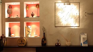 A reception area with a 'Paris Café' sign, decorative items on shelves, a wall-mounted light fixture, and a 'Bagnoli' sign. - Miramonti (Potenza)