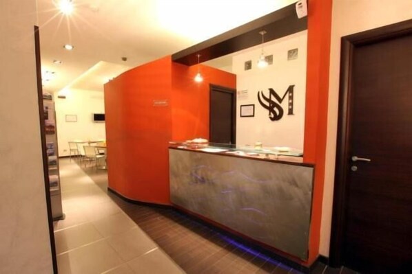 A reception area with a marble counter, a black and white logo on the wall, and a door to the right.
