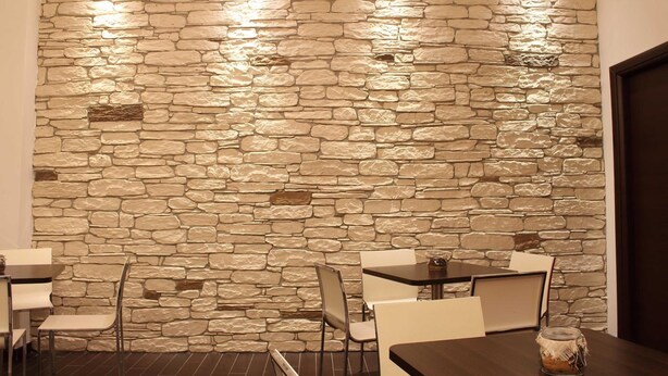 A room with a stone wall, several tables and chairs, and a door. - Miramonti (Potenza)