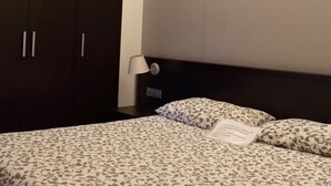 A hotel room with a large bed, dark wooden wardrobe, and a bedside table with a lamp. - Miramonti (Potenza)