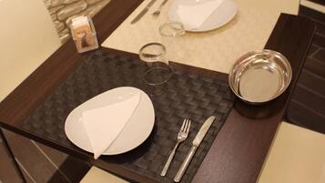 A dining table set with plates, cutlery, and glasses, with a stone wall in the background.