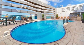 A rooftop pool with a clear view of the city skyline, surrounded by lounge chairs and a bar area. - Al Manzel Hotel Apartments (Abu Dhabi)