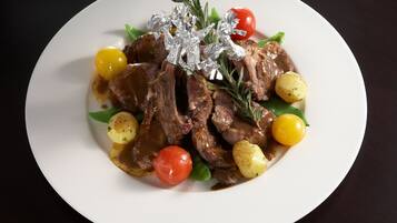 A plate of food with meat, potatoes, and cherry tomatoes.