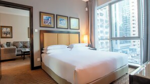 Ein Hotelzimmer mit einem großen Bett, einer Sitzecke, einem Schreibtisch und einem Fenster mit Blick auf die Stadt.