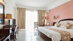 A hotel room with a bed, a desk, a chair, a TV, and a window with curtains. - Lihua Hotel Haikou (Haikou)