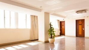A spacious hotel lobby with a polished floor, large windows with curtains, and a potted plant. - Lihua Hotel Haikou (Haikou)