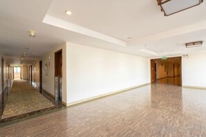 A hotel corridor with a marble floor, doors on the left, and a green exit sign on the right. - Lihua Hotel Haikou (Haikou)