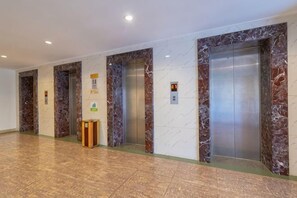A hallway with marble-topped elevators and a trash bin. - Lihua Hotel Haikou (Haikou)
