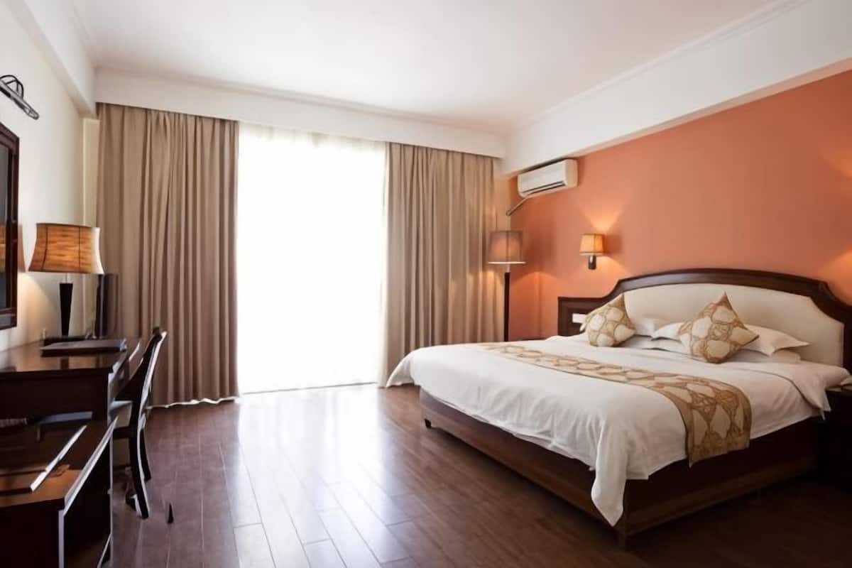 Quarto de hotel com uma cama grande, uma escrivaninha e uma cadeira.