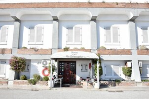 A hotel with a white facade, multiple windows with shutters, and a sign reading "Hotel La Trippigola".
