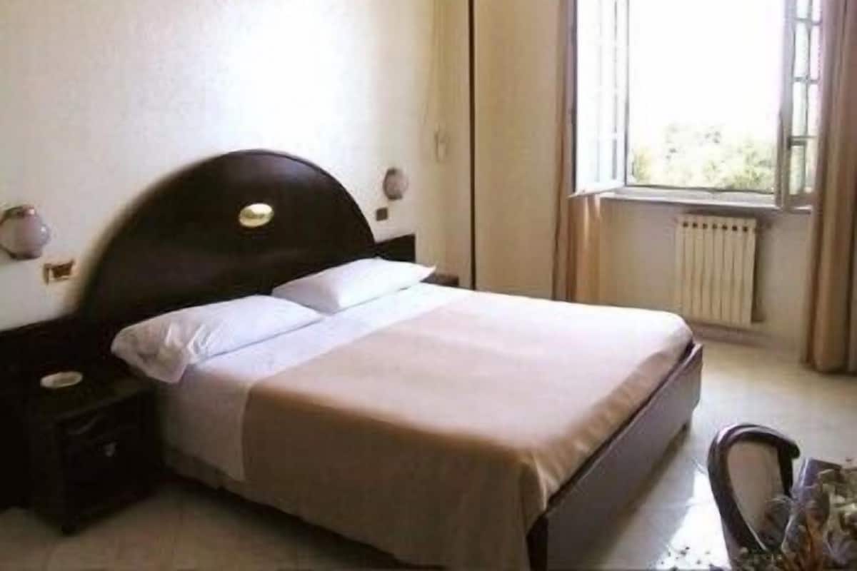 A single bed in a room with a window, a radiator, and a nightstand.