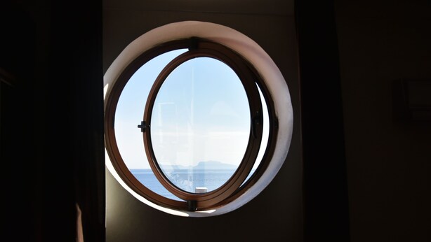 Una ventana redonda con vista a un paisaje montañoso.