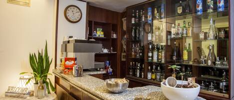 A bar area with a granite countertop, a welcome sign, a clock, and a glass display case with bottles.