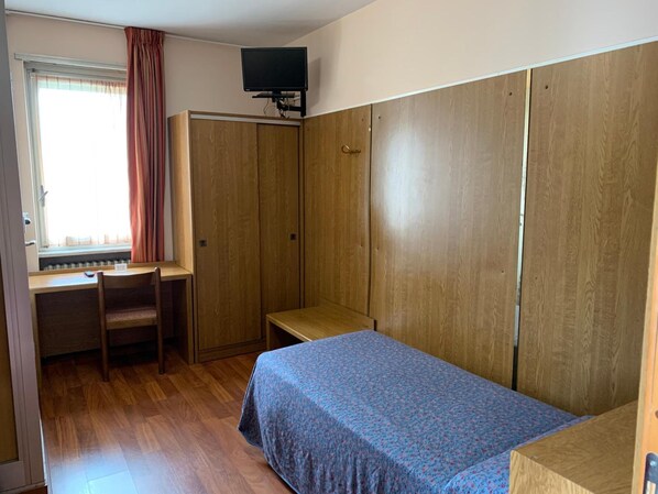 Ein Zimmer mit einem Bett, einem Schreibtisch und einem Kleiderschrank.