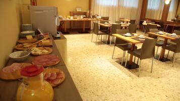 Ein Essbereich mit einer Buffet-Anrichtung, darunter verschiedene Speisen und ein Kühlschrank.