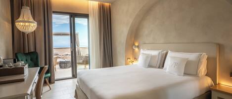 A hotel room with a large bed, a desk, a chair, and a view of the sea through a sliding door.