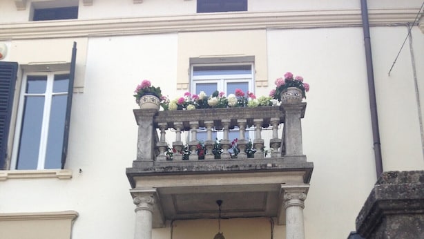 Un bâtiment doté d’un balcon orné de fleurs, d’une enseigne indiquant « chambre d’hôtes » et d’un portail.