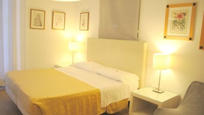 Une chambre d’hôtel comprenant un lit, des tables de chevet, une chaise et des œuvres d’art accrochées au mur.