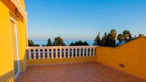 A balcony with a tiled floor and a white balustrade, overlooking a body of water and trees. - Kione Anamar (Alcala de Xivert)