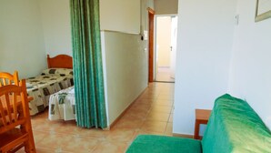A room with a bed, a chair, a small table, and a curtain. - Kione Anamar (Alcala de Xivert)