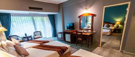 Een hotelkamer met twee bedden, een bureau met een computer, een stoel, een televisie en een spiegel.