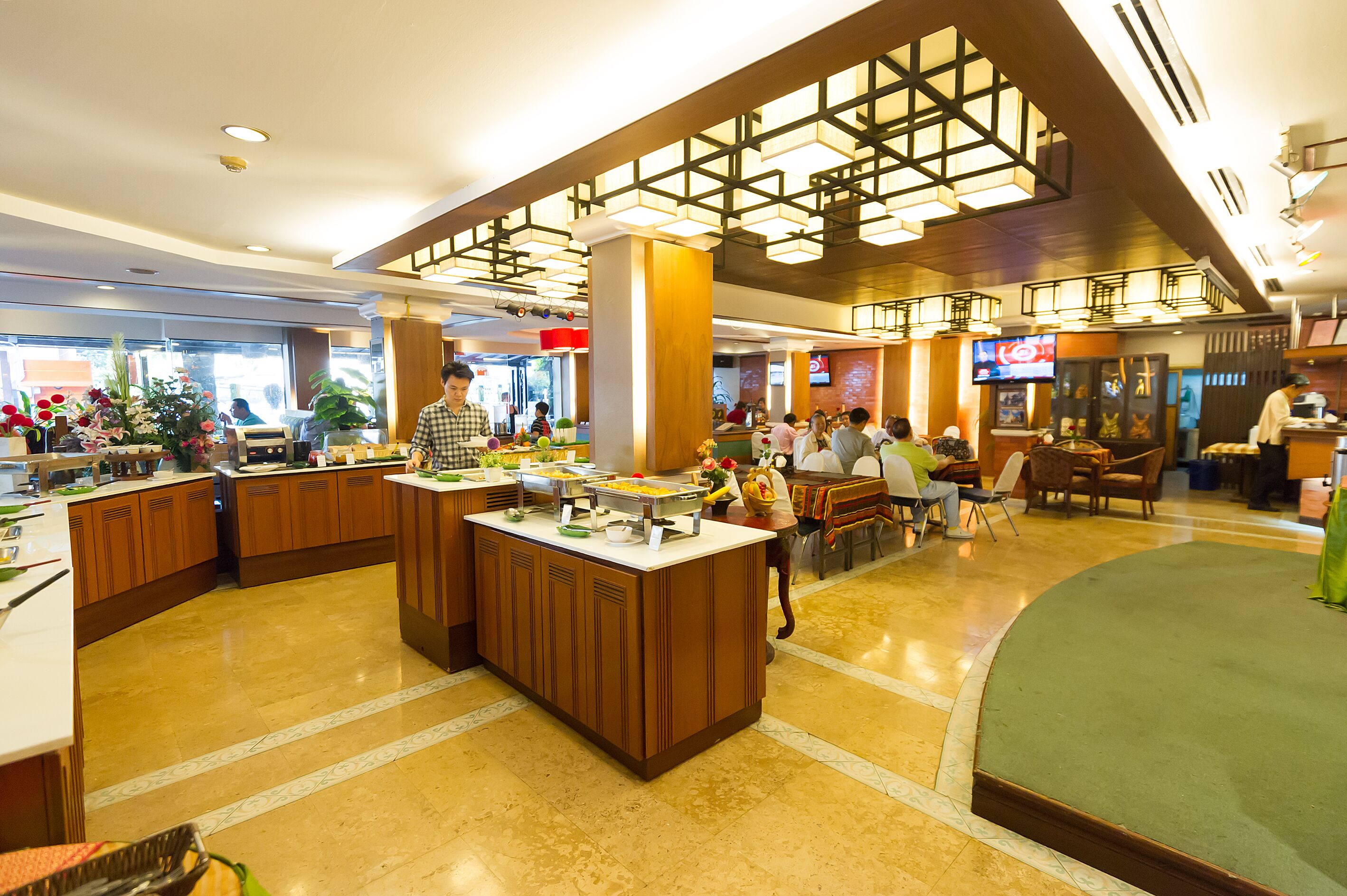 A spacious hotel lobby with a central island, seating areas, and a modern ceiling design.