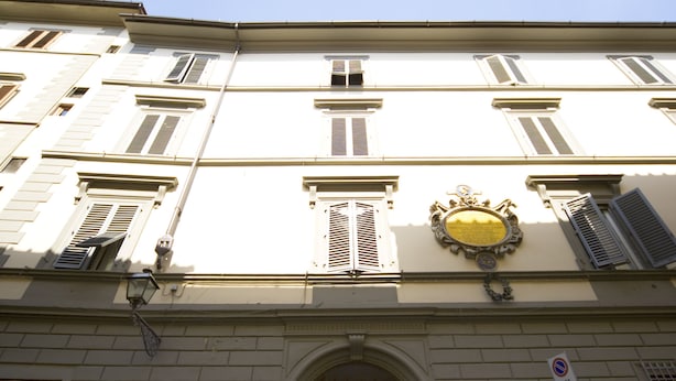 A building facade with a central entrance, multiple windows with shutters, and a decorative emblem above the entrance. - Hotel Merlini (Florence)