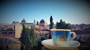 A cup on a saucer with a view of a cityscape, including buildings and a dome structure. - Hotel Merlini (Florence)