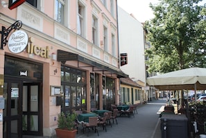 A café with outdoor seating, a sign for 'Radler Biergarten Café', and a nearby 'Pension' building. - Pension Unicat (Potsdam)