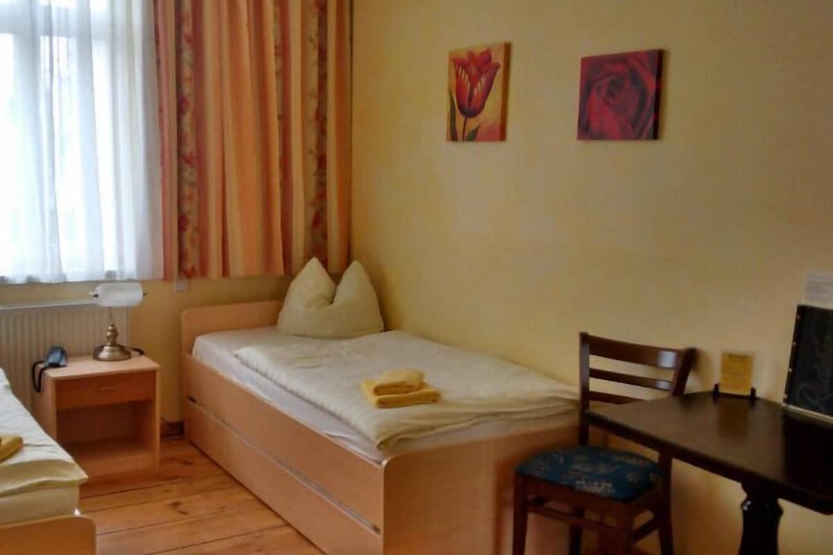 Habitación de hotel con dos camas, un escritorio, una silla y dos cuadros en la pared.