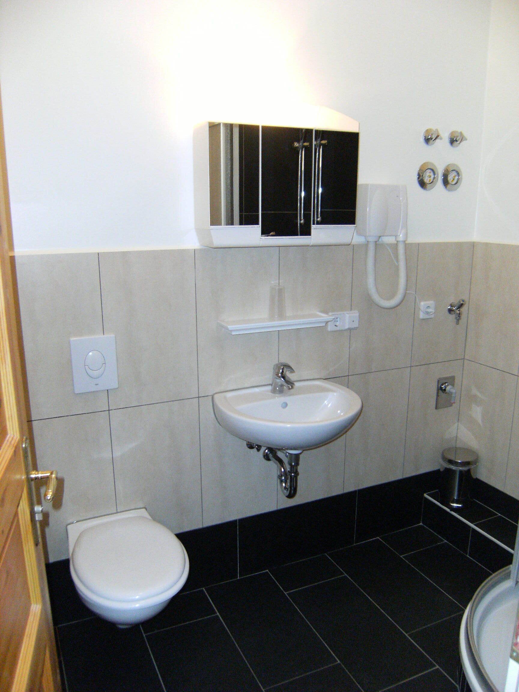 A bathroom with a toilet, sink, and a cabinet above the mirror.