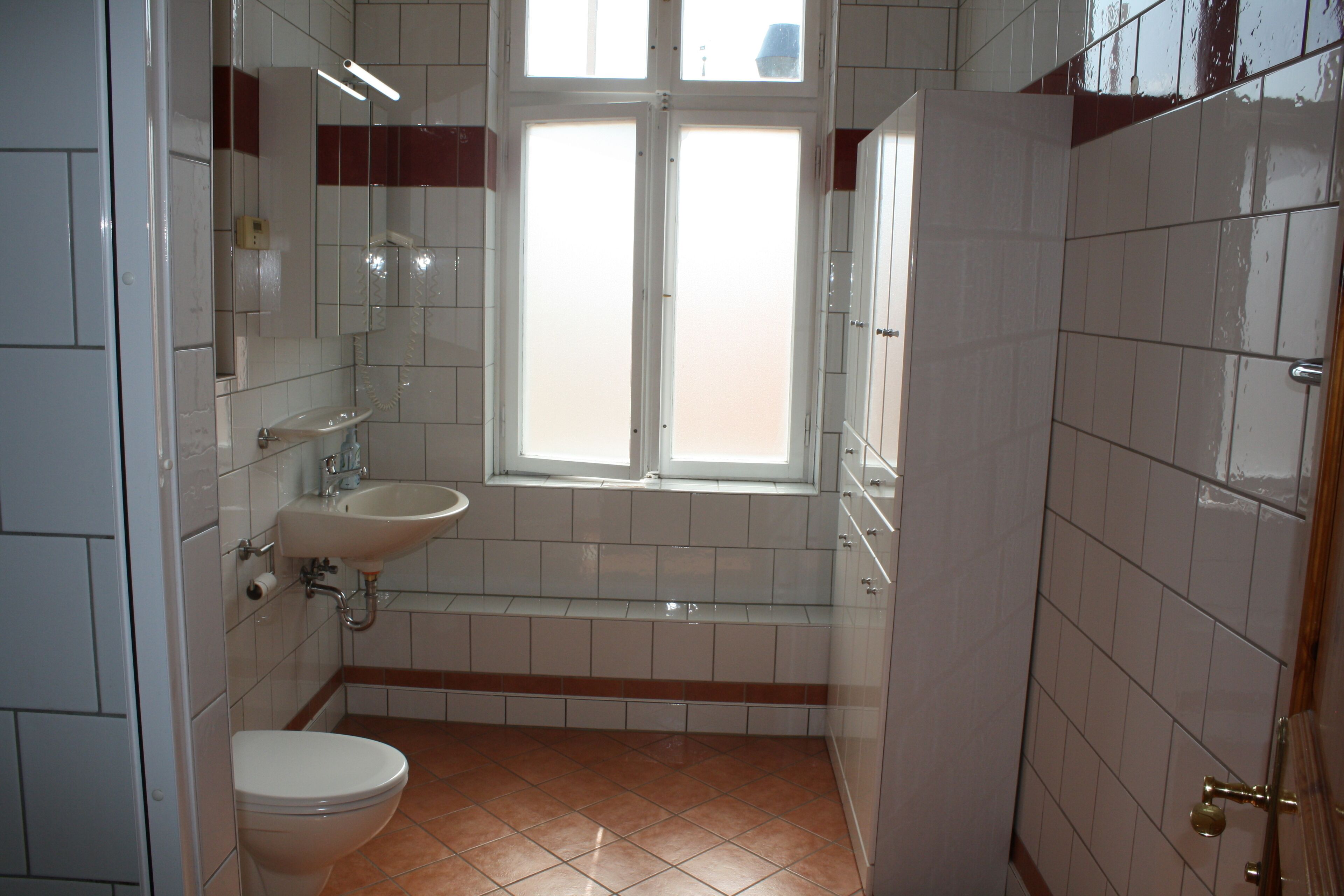 Een badkamer met toilet, wastafel en raam.