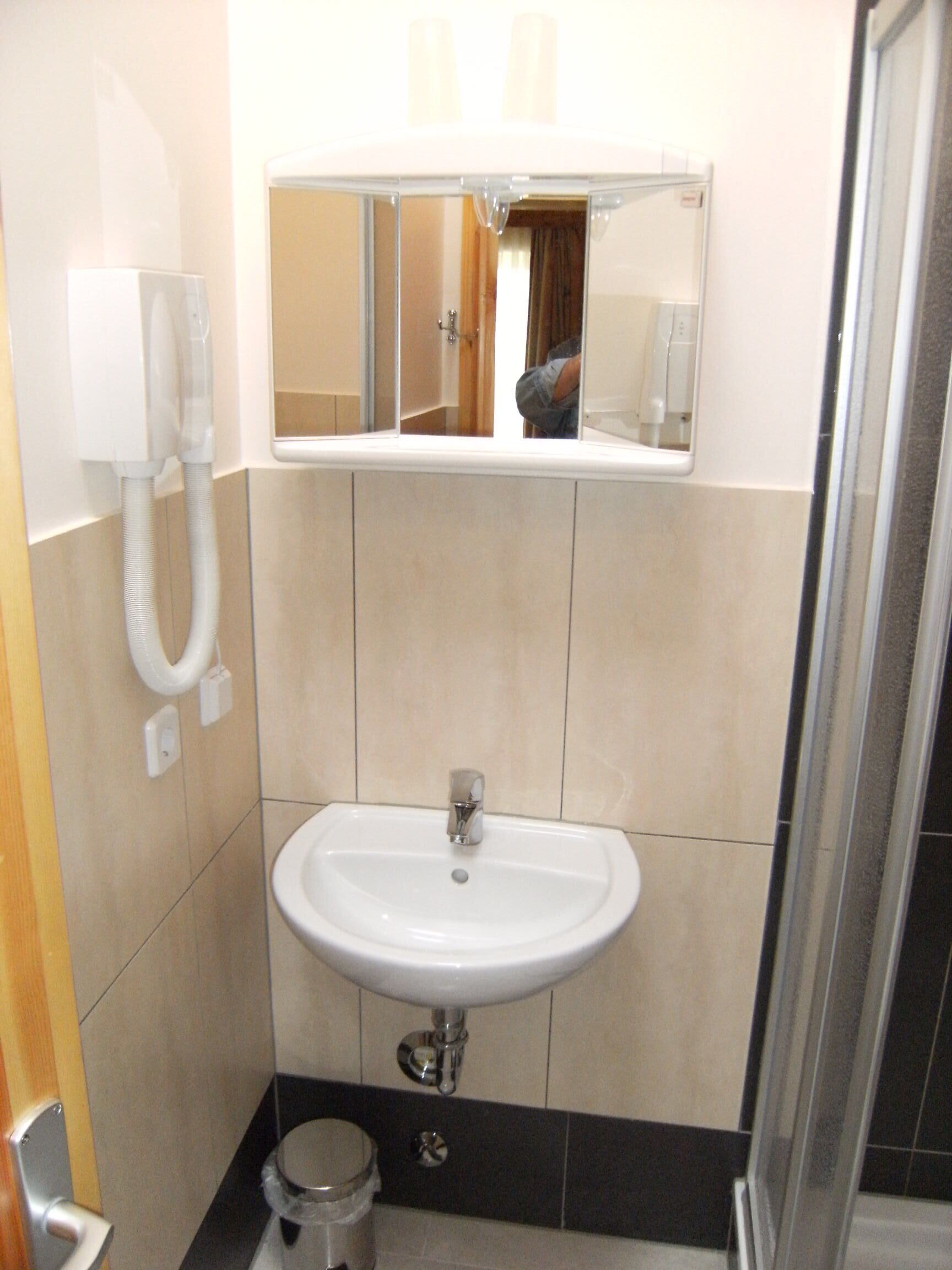 A bathroom with a white sink, a mirror, and a hand dryer.