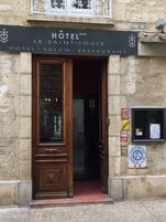 La entrada a un hotel con un letrero que dice "HOTEL LE SAINT-LUIS HOTEL SALON RESTAURANT".