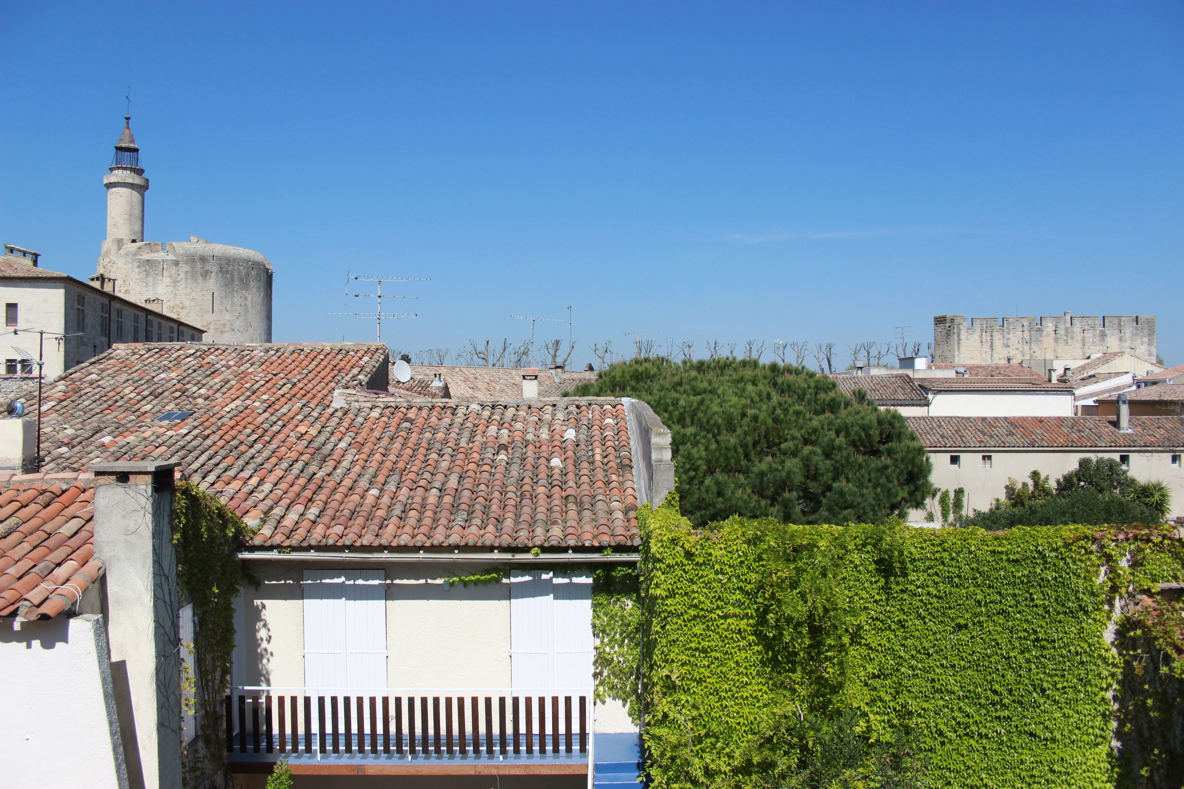 Un edificio con techo de tejas, una chimenea y una pared blanca con un ventanal.