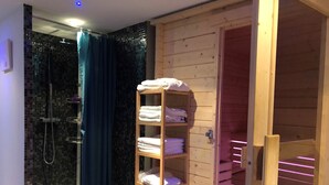 Una cabaña de madera con zona de ducha y estante de madera con toallas.