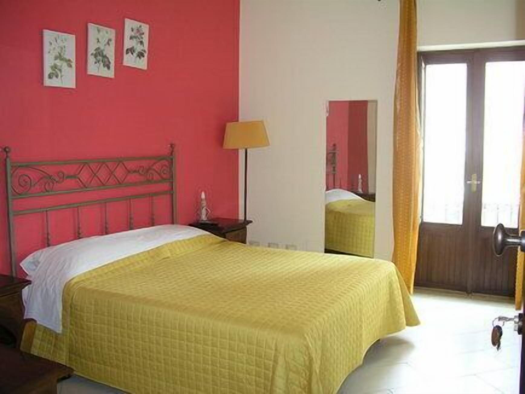 A room with a bed, a nightstand, a lamp, and a mirror.