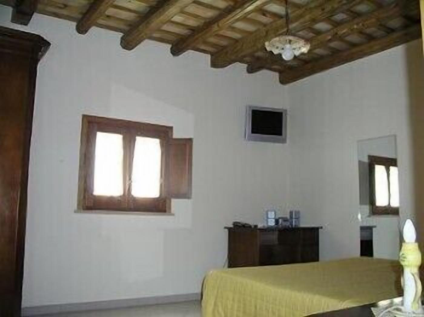 A bedroom with a wooden ceiling, a bed with a yellow bedspread, a dresser, a small window, and a mirror.