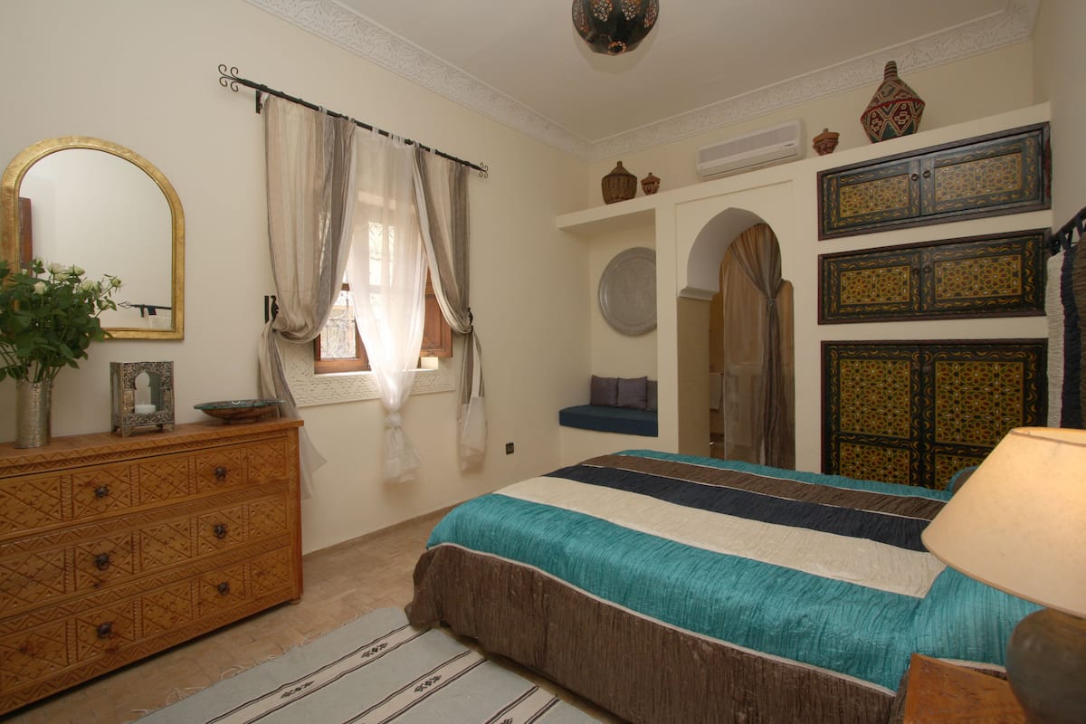 A bedroom with a bed, dresser, mirror, and decorative items.