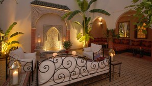 Un rincón de sala acogedor con un muro estampado, una disposición de asientos y una fuente decorativa.