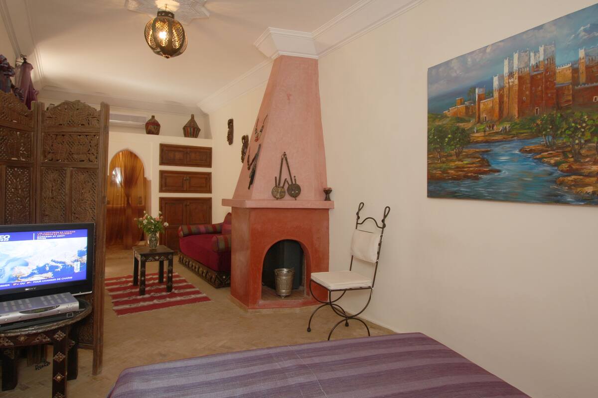 A living room with a fireplace, a television, and a painting of a castle.