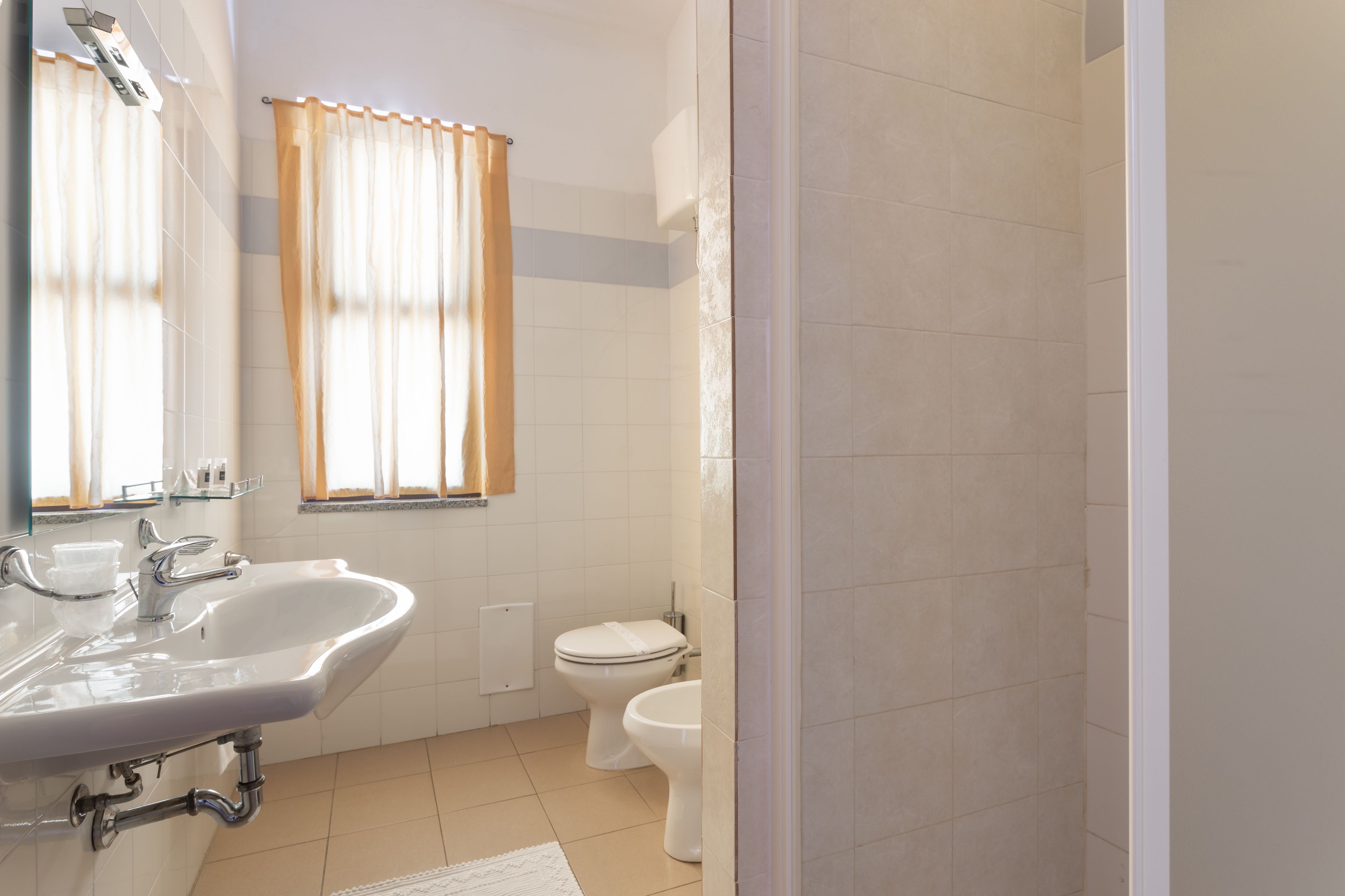 Une salle de bain équipée d’un lavabo, d’un miroir, de toilettes et d’un espace douche.