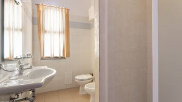 Une salle de bain équipée d’un lavabo, d’un miroir, de toilettes et d’un espace douche.