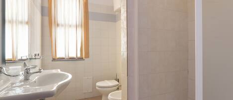 A bathroom with a sink, mirror, toilet, and shower area.