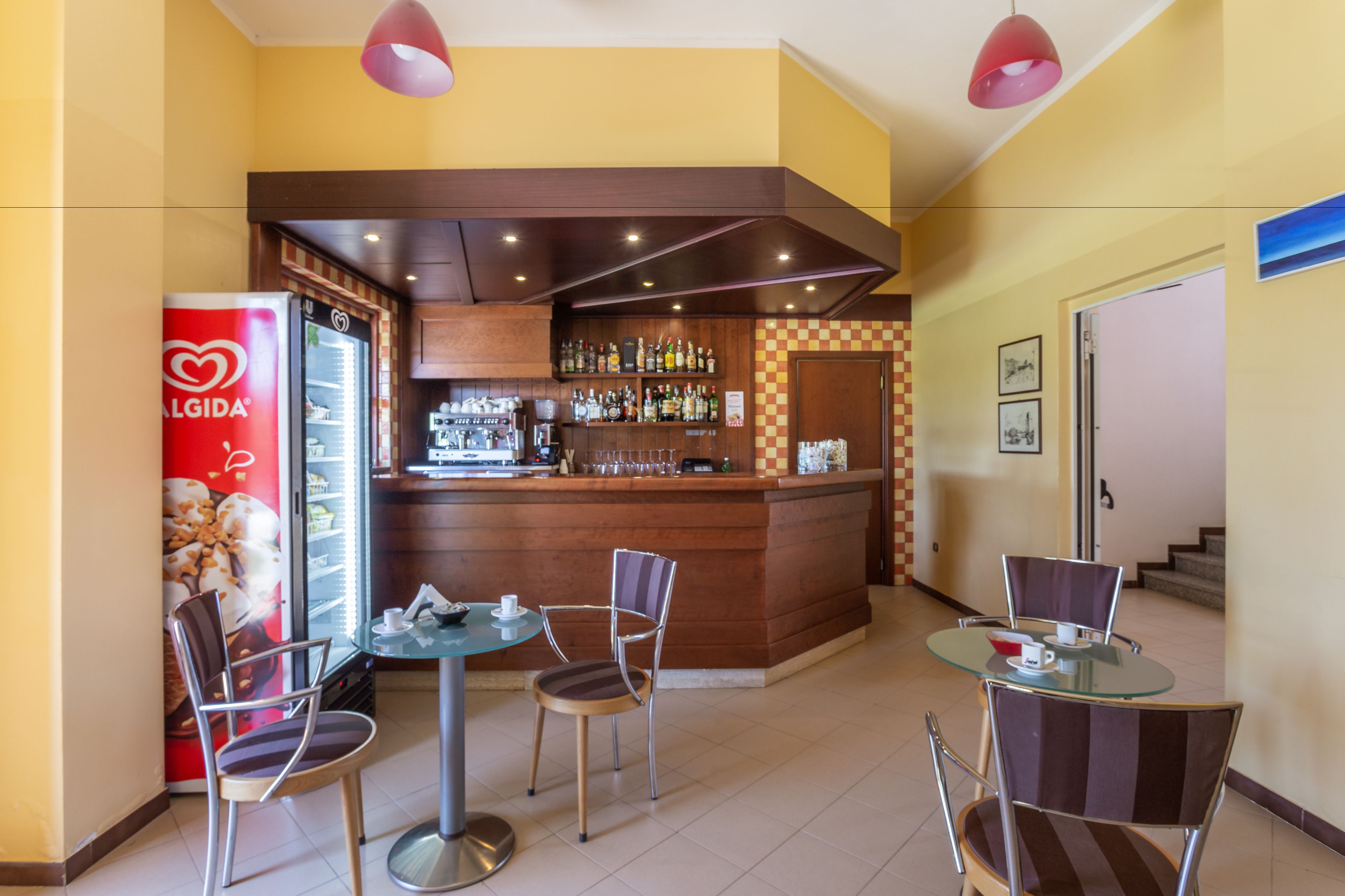 A bar area with a counter, stools, and a refrigerator.