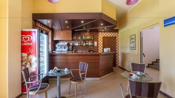 A bar area with a counter, stools, and a refrigerator.