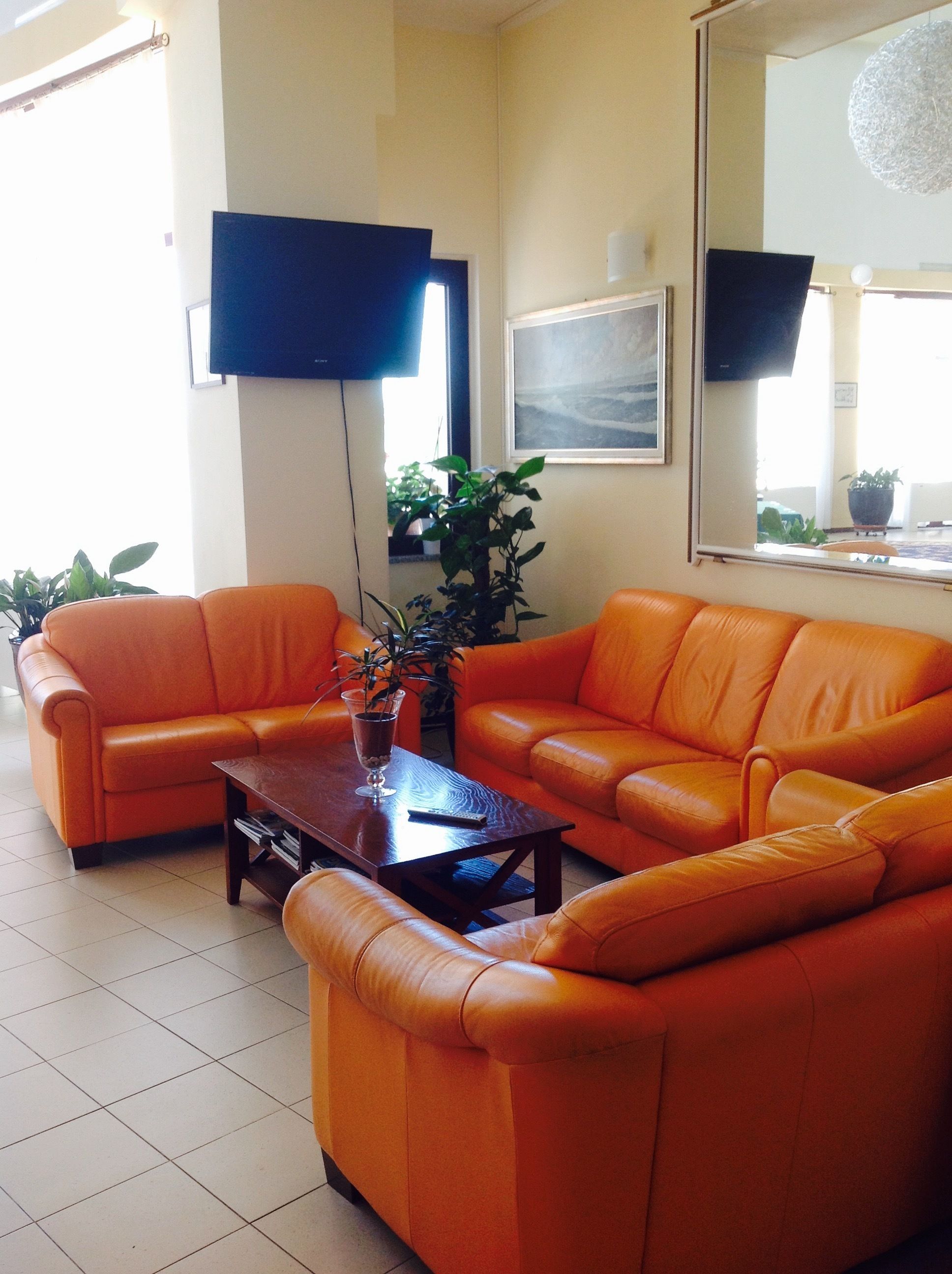 A living room with orange leather sofas, a wooden coffee table, and a flat-screen TV mounted on the wall.