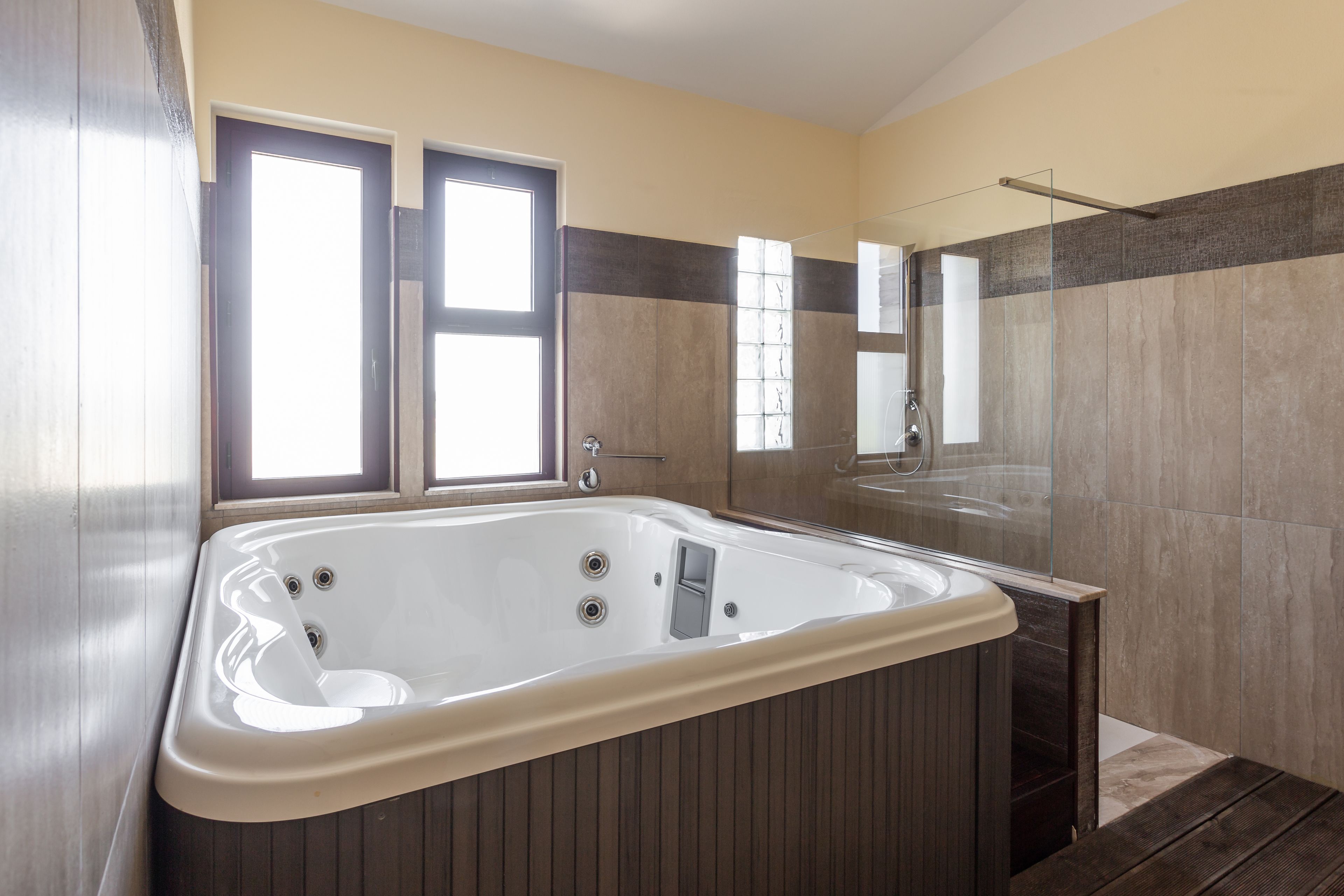 A modern bathroom with a large bathtub, a glass shower enclosure, and a mirror above the sink.
