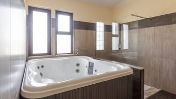 A modern bathroom with a large bathtub, a glass shower enclosure, and a mirror above the sink.