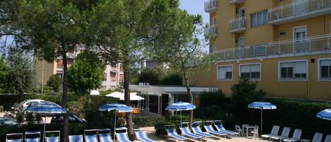 Una piscina al aire libre, sombrillas, sillones reclinables de piscina